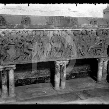 Sarcofago sorretto da sei colonne binate e con frontale interamente scolpito a bassorilievo con figure in atto di ossequio verso una figura posizionata a sinistra nell'opera, su un trono.

Archivio fotografico del Museo Didattico della Fotografia (MUDIF)